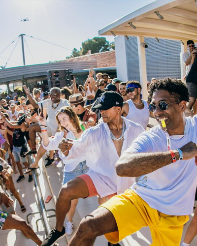 Eine lebhafte Party im Freien, bei der die Menschen energisch in der Sonne tanzen.