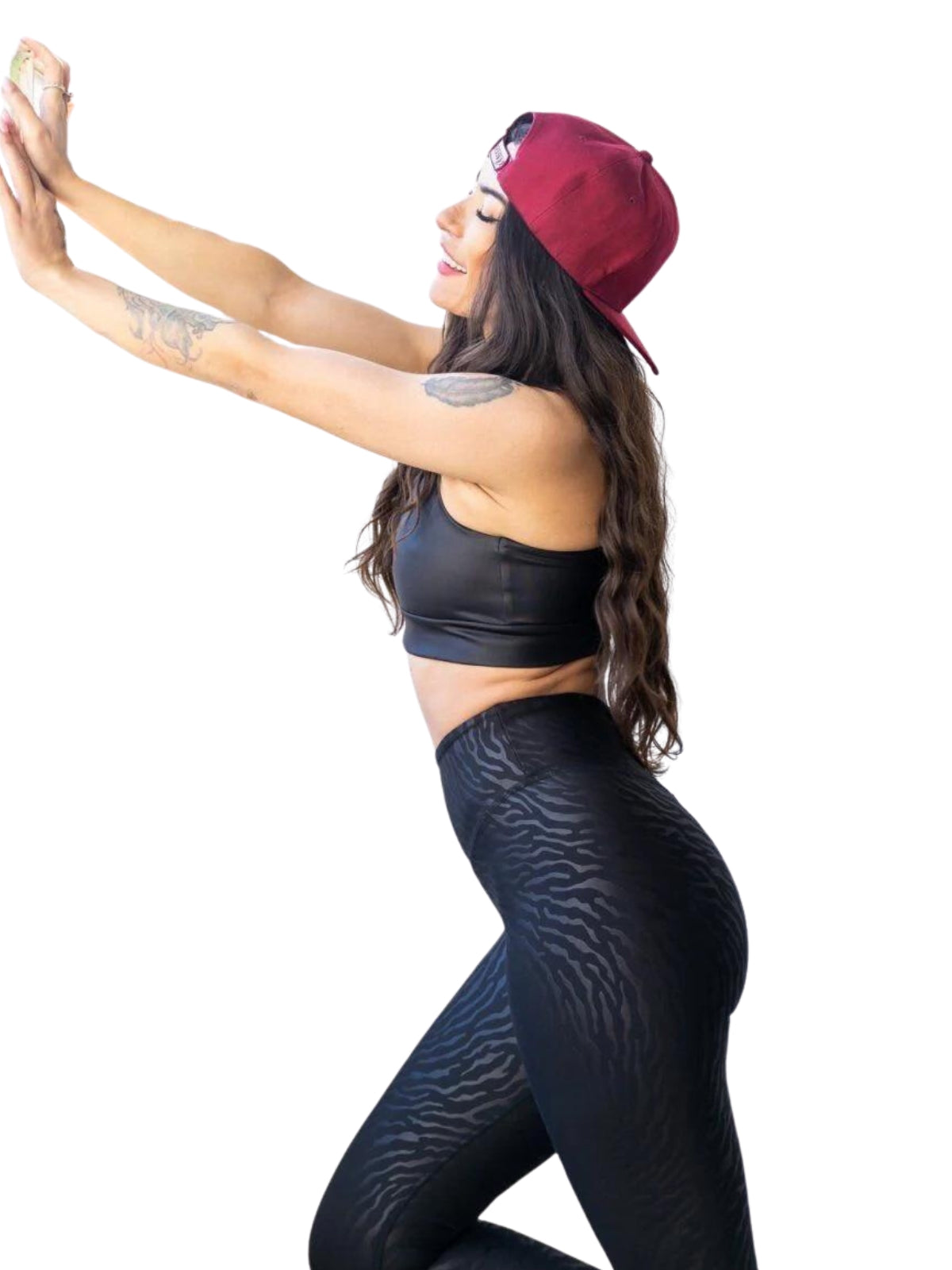 Frau mit roter Mütze und schwarzem Oberteil posiert mit ausgestreckten Armen und trägt Lisminas 1194 Leggings in Lederoptik in Schwarz.