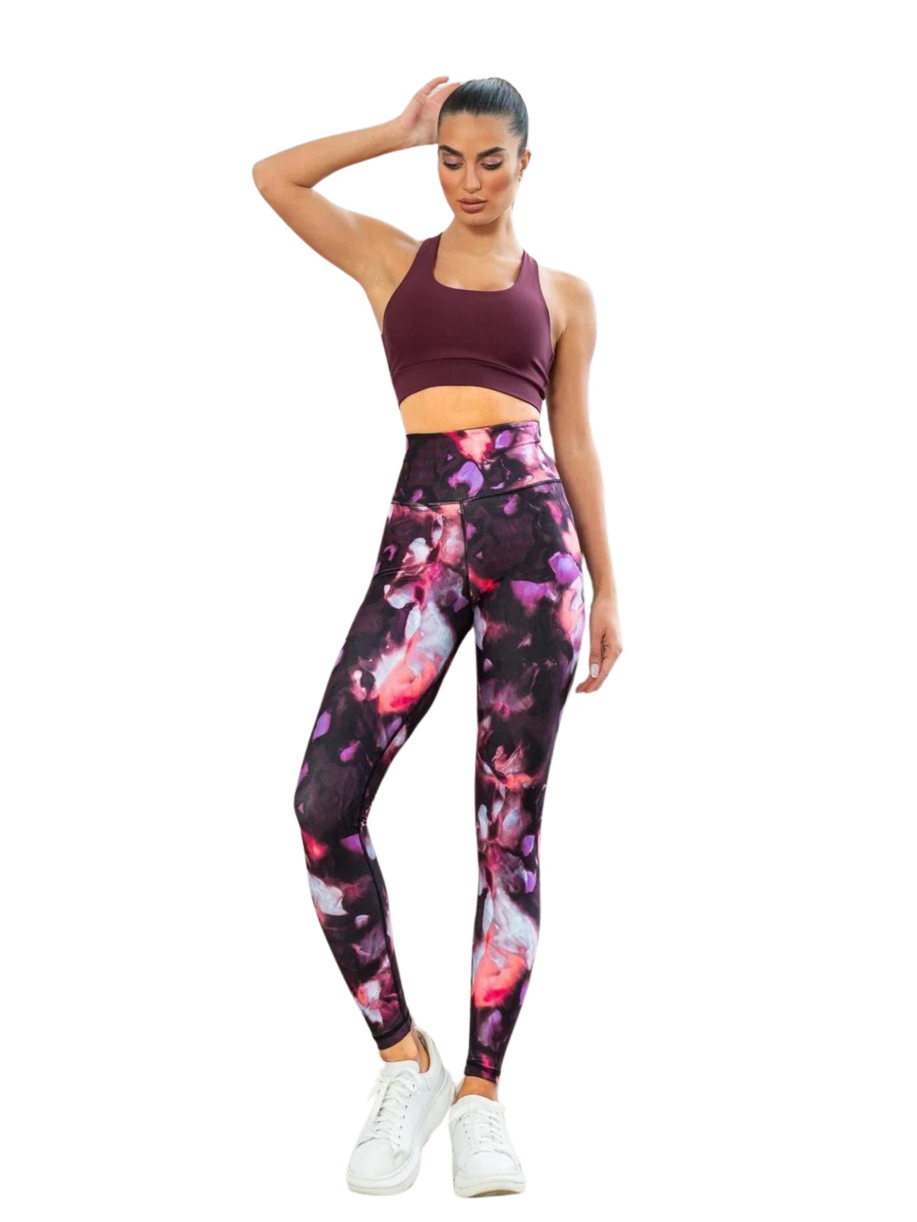 Frau in Lisminas 413 High Waist Leggings in Rosa-Schwarz, kastanienbraunem Sport-BH und weißen Turnschuhen posiert mit der Hand auf dem Kopf.