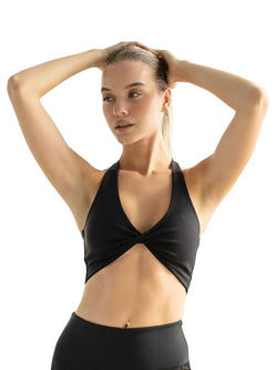 Person, die Lisminas 391 Saintes Sport-BH in Schwarz trägt, macht eine Yoga-Pose, Hände auf dem Kopf, Blick zur Seite.