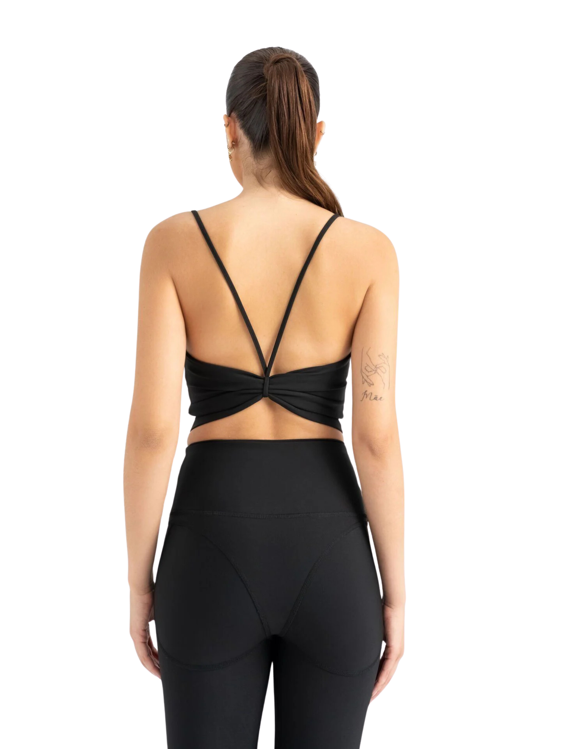 Frau im 530 Knot Sport Bra in Schwarz von Lismina und schwarzen Leggings, von hinten vor weißem Hintergrund.