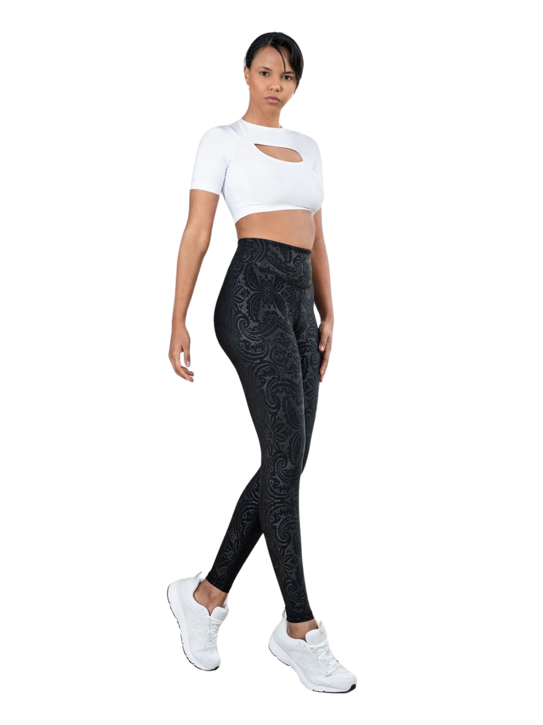 Person in Lisminas 467 Bilboa-Leggings in Lederoptik, einem weißen bauchfreien Top und weißen Turnschuhen, die selbstbewusst geht.