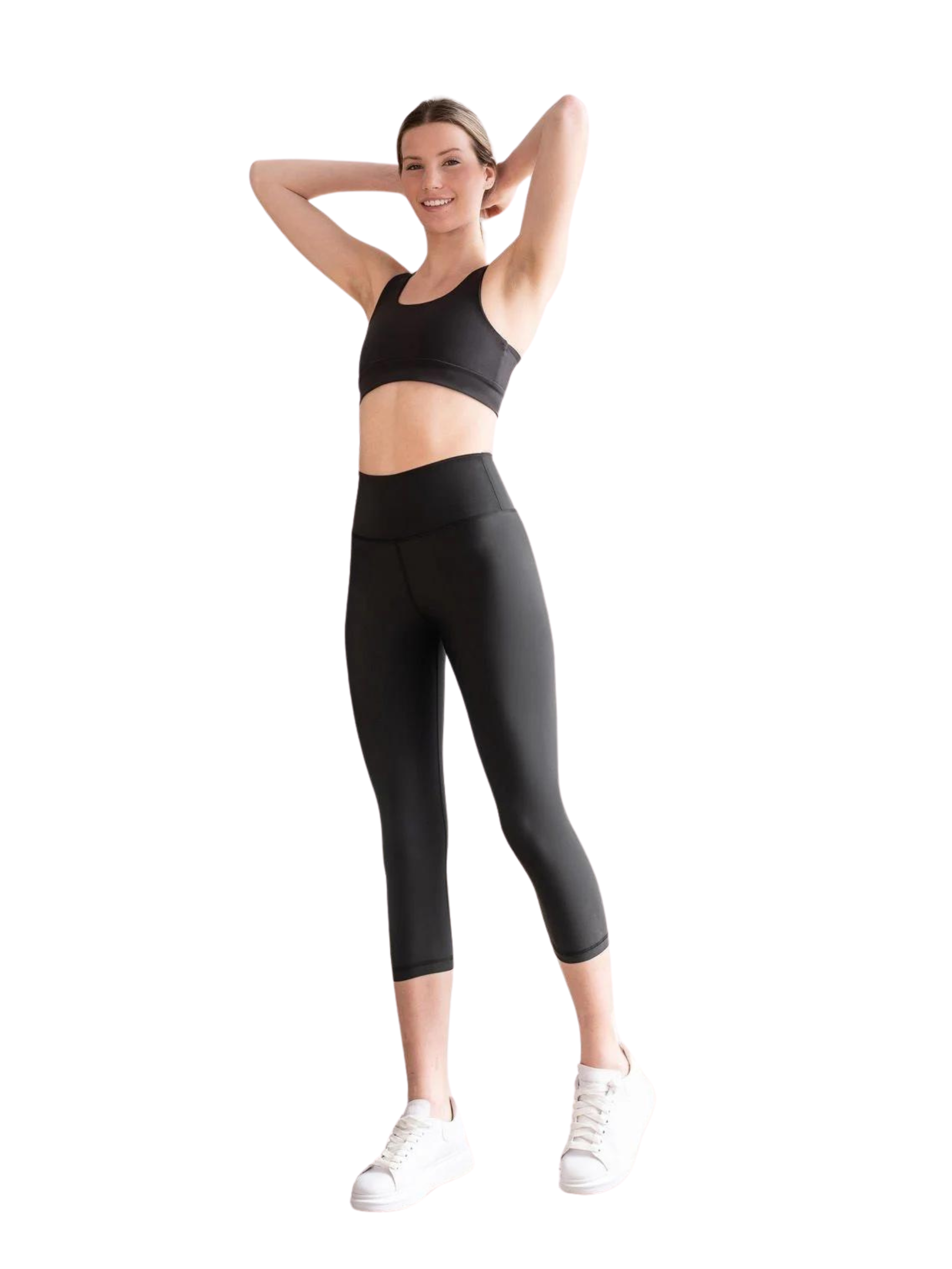 Eine Person in schwarzer Sportkleidung und weißen Turnschuhen, darunter Lisminas 4306 Capri Leggings in Schwarz, lächelt.