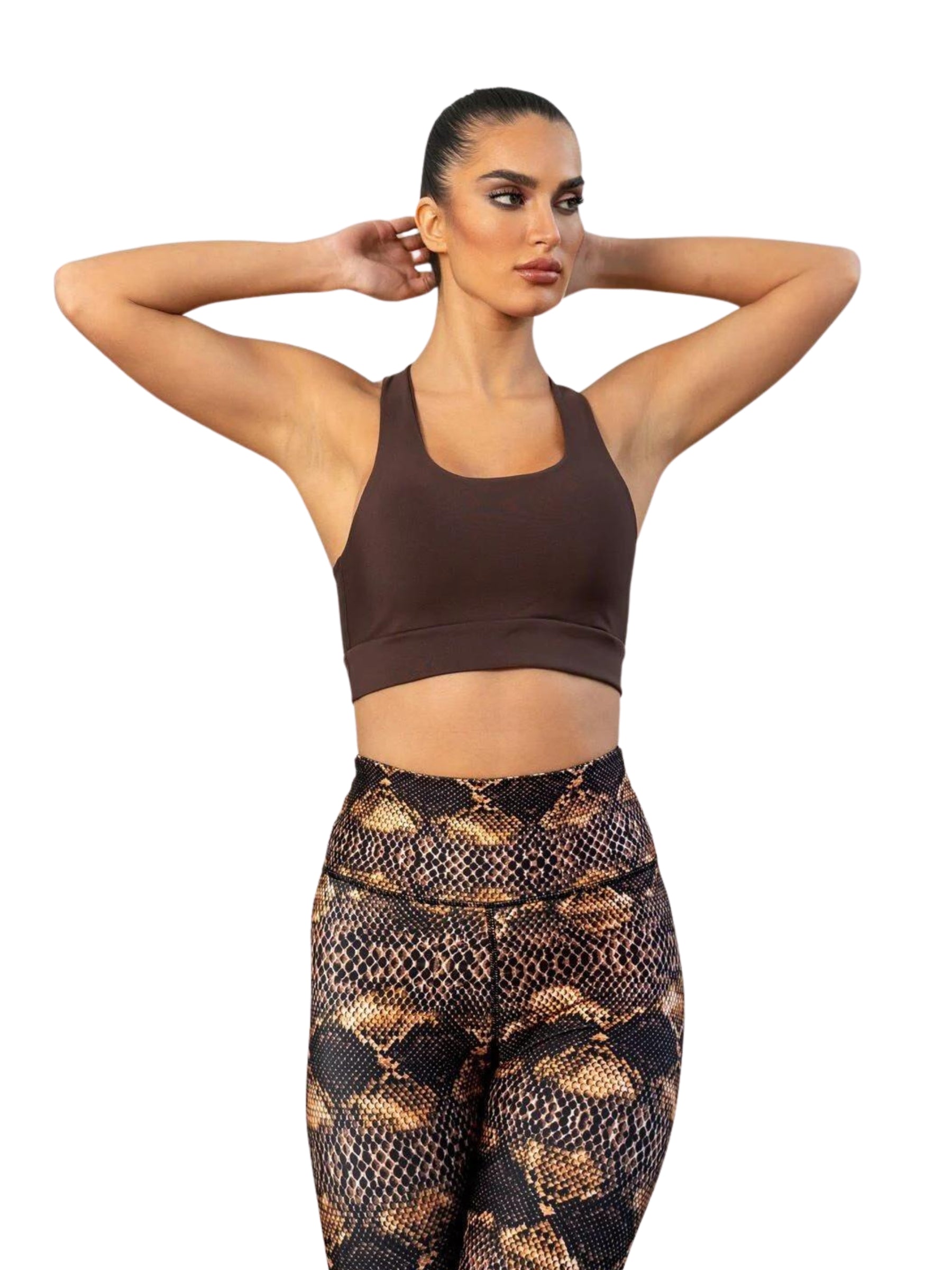 Person in einem braunen Lismina-Sport-BH und 411 High Waist Leggings, die Arme vor weißem Hintergrund erhoben.