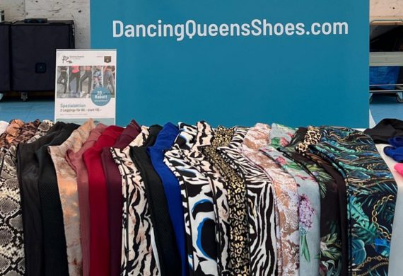 Eine Ausstellung farbenfroher Kleidungsstoffe mit verschiedenen Mustern unter einem „DancingQueensShoes.com“-Schild.