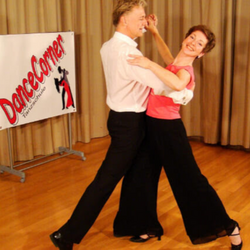 Ein Paar tanzt in einem Studio neben einem Tanzkurse-Banner, das für DanceCorner wirbt.