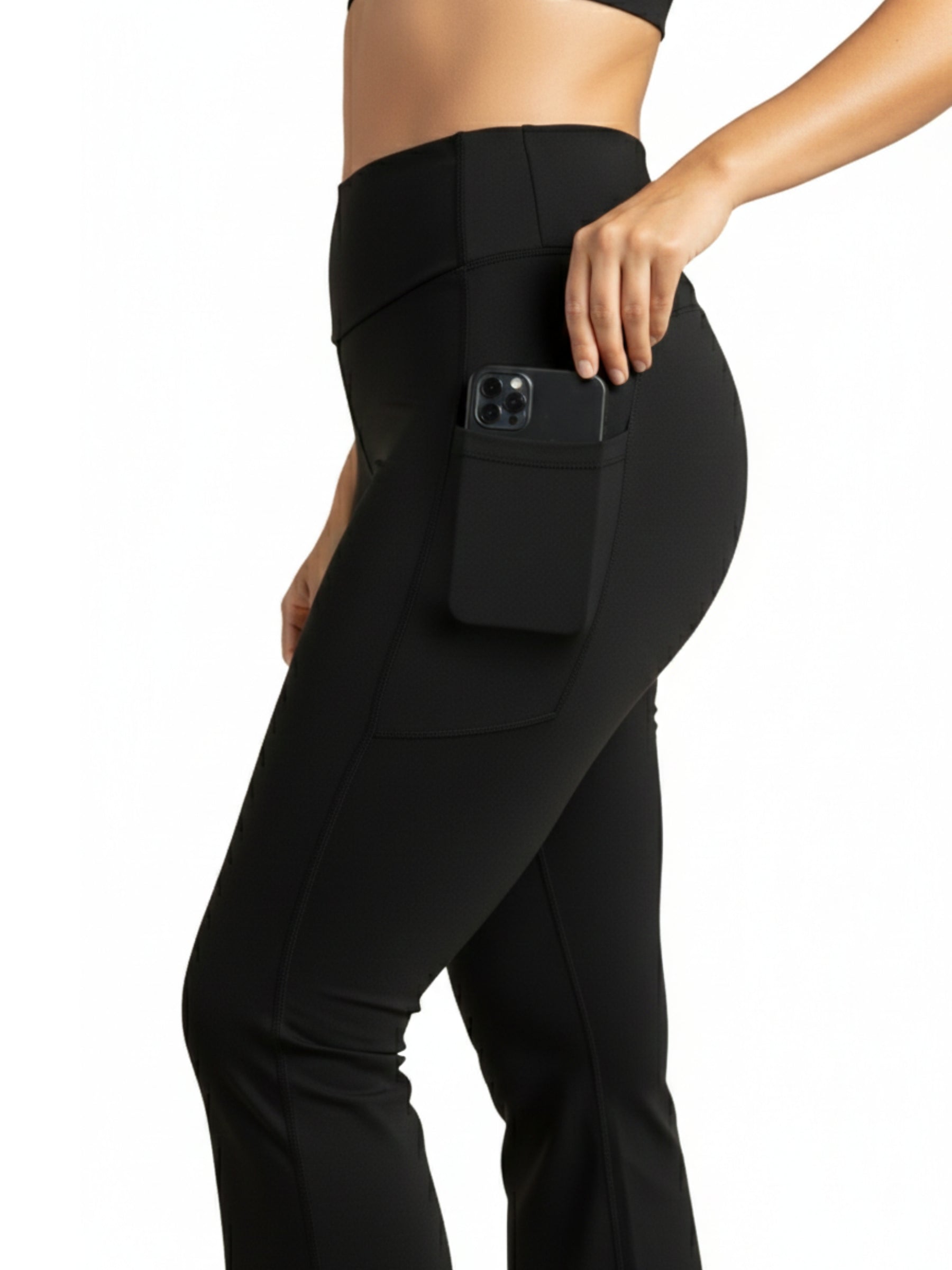 Frau trägt Dancing Queens Luna Flare Pocket Leggings in Schwarz, Telefon in der Seitentasche, Ansicht Taille bis Mitte Oberschenkel.