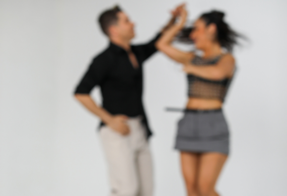 Ein unscharfes Bild von zwei tanzenden Menschen vor einem schlichten Hintergrund.