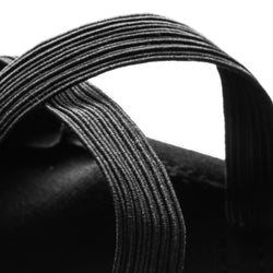 Nahaufnahme der schwarzen strukturierten Riemenschlaufe des Rumpf 1006 Elastico Ballettschläppchen auf weißem Hintergrund, die Flexibilität zeigt.