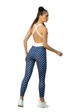 Frau in einem 1321 Single Cross Jumpsuit von Lismina, leicht gedreht, trägt schlank machende weiße Sneakers.
