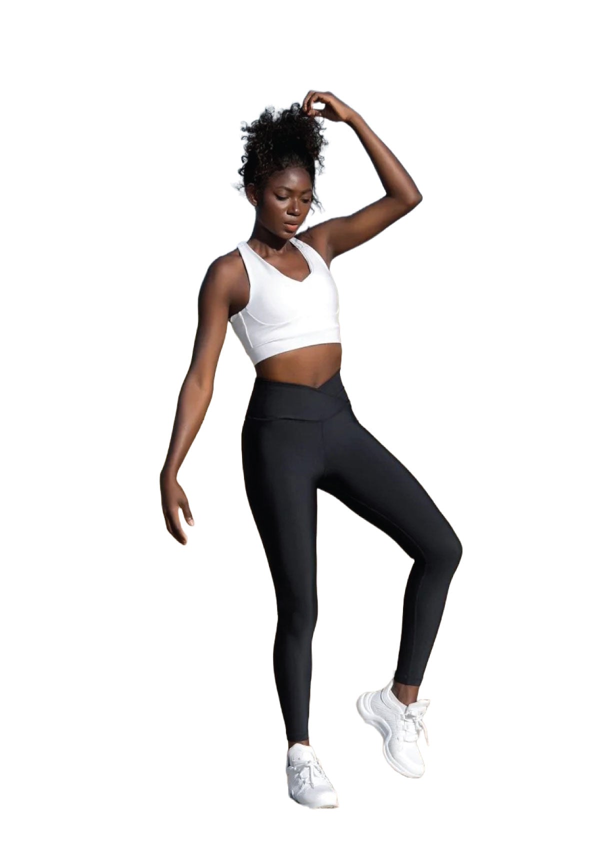 Person in Sportkleidung posiert vor einem weißen Hintergrund, trägt einen Lismina 189 Sport-BH in Weiss, schwarze Leggings und weiße Turnschuhe.