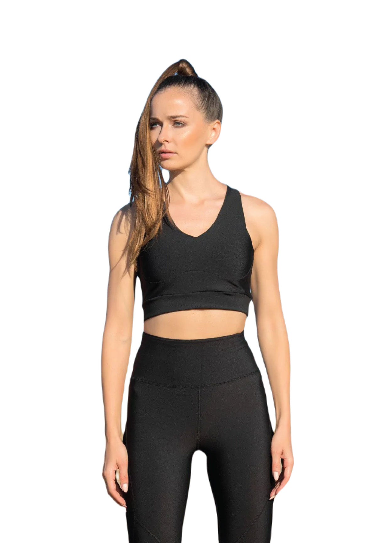 Eine Frau in einem Lismina 188 Sport-BH in Schwarz mit Pferdeschwanz steht vor einem weißen Hintergrund.