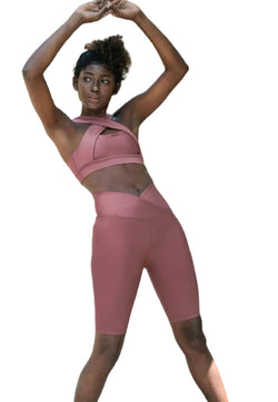 Eine Person in Lisminas 6027 Biker Leggings Ve Waist in Dark Rose streckt vor einem weißen Hintergrund die Arme über den Kopf.