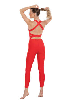 Person in Esmeraldas Lily-Jumpsuit in Rot, barfuß, von hinten gesehen, bindet Haare für Yoga.