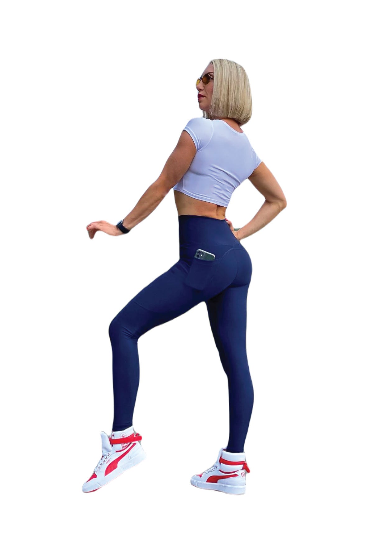 Person in Trainingskleidung, Seitenansicht, trägt ein bauchfreies Top von Lismina, 988 Pocket Leggings in Marineblau, Turnschuhe und eine Sonnenbrille.