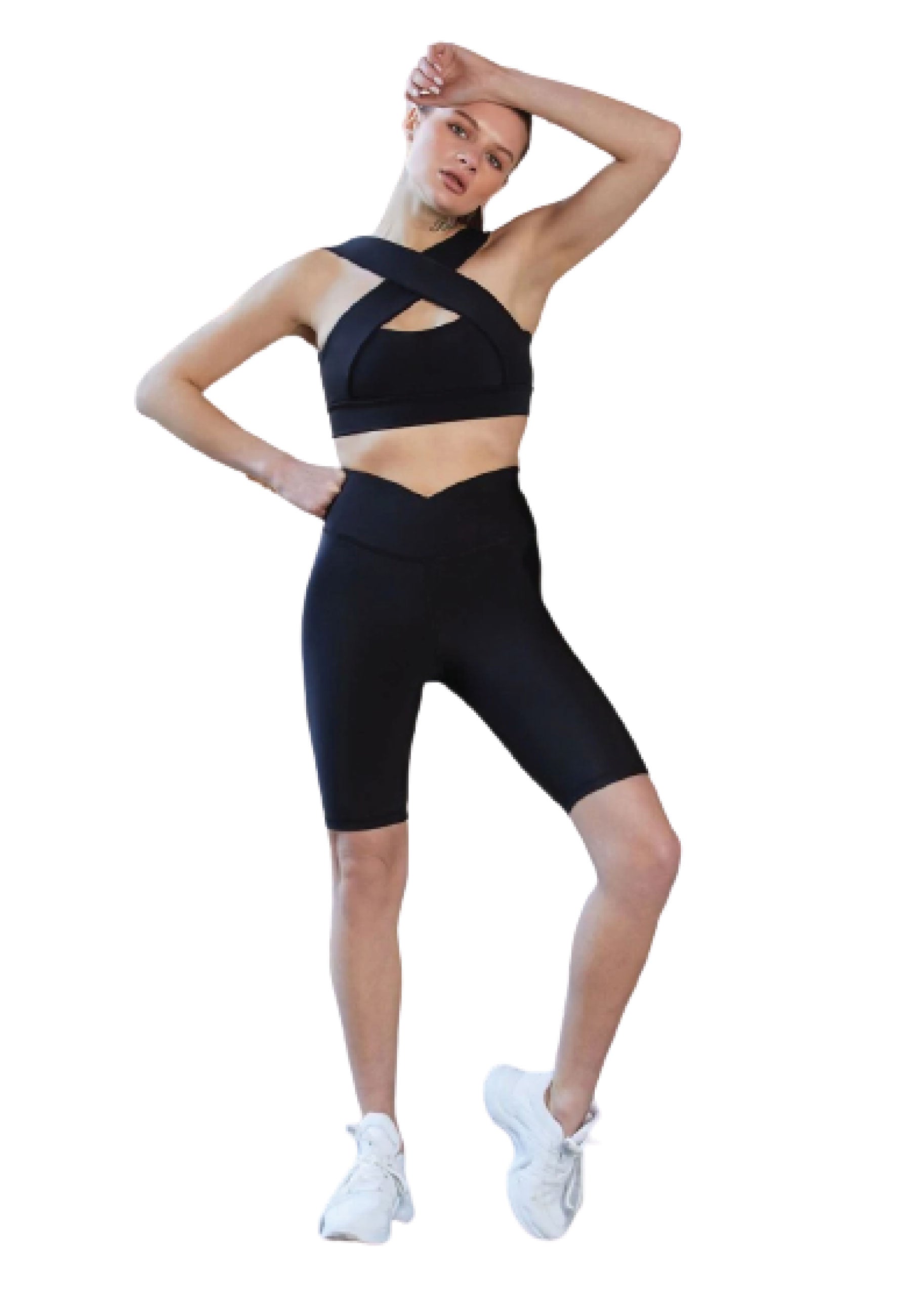 Person in Lisminas 6010 Biker-Leggings Ve Waist in Schwarz und weißen Turnschuhen, die anmutig mit einem erhobenen Arm posiert.