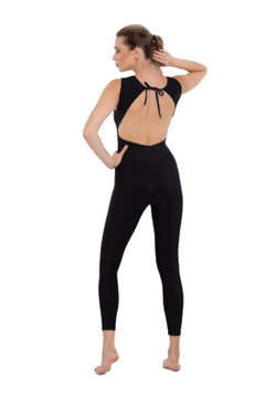 Eine Person in einem schwarzen Esmeralda Mia-Jumpsuit steht barfuß in einer Yoga-Pose, die Hände auf den Hüften, mit dem Gesicht abgewandt.