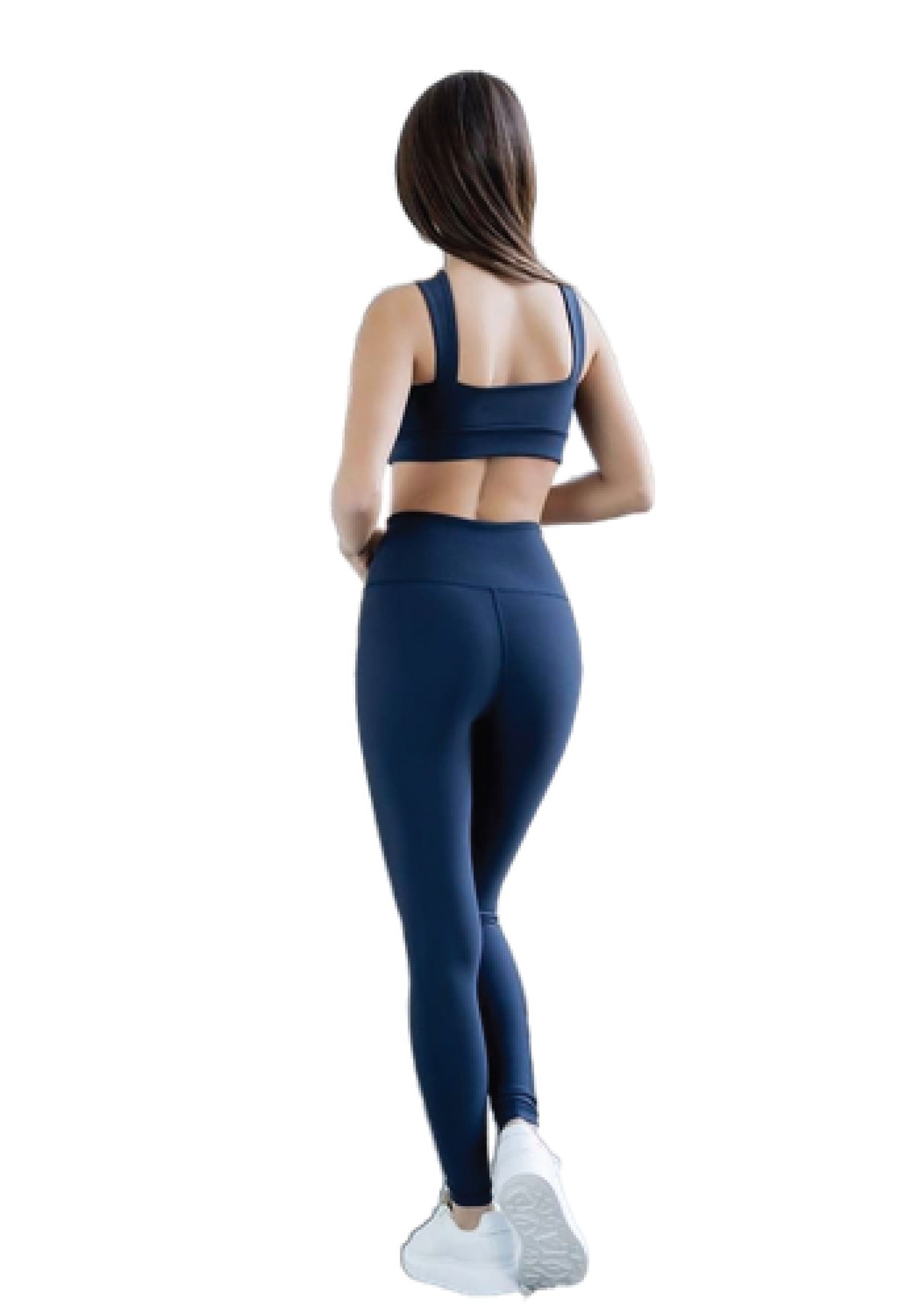 Person in Lisminas Navy Blau 200 Decoltée Sport-BH und Leggings, perfekt für Yoga, leicht nach links blickend in weißen Sneakers.