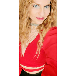 Lockiges blondes Haar, rotes Oberteil, Halskette; Eine Tanzpädagogin in Düsseldorf strahlt für Salsa con Irini Panderis von Tanzkurse.