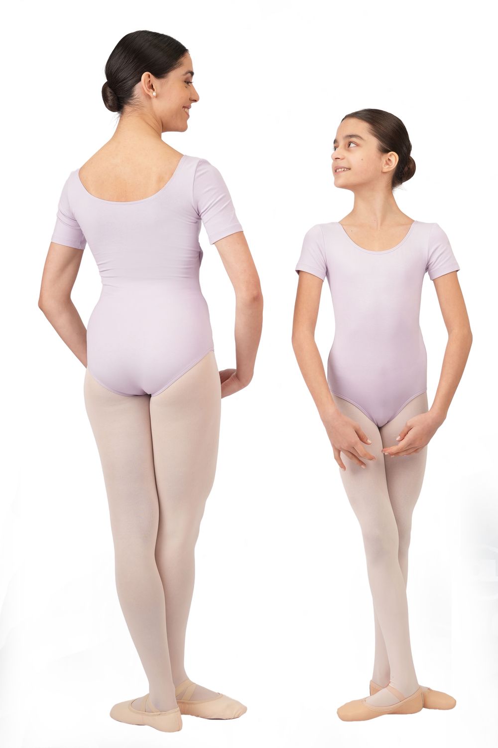 Zwei Personen im Kurzarm-Body R3100 von Rumpf in Lila und beiger Strumpfhose posieren einander lächelnd gegenüber.