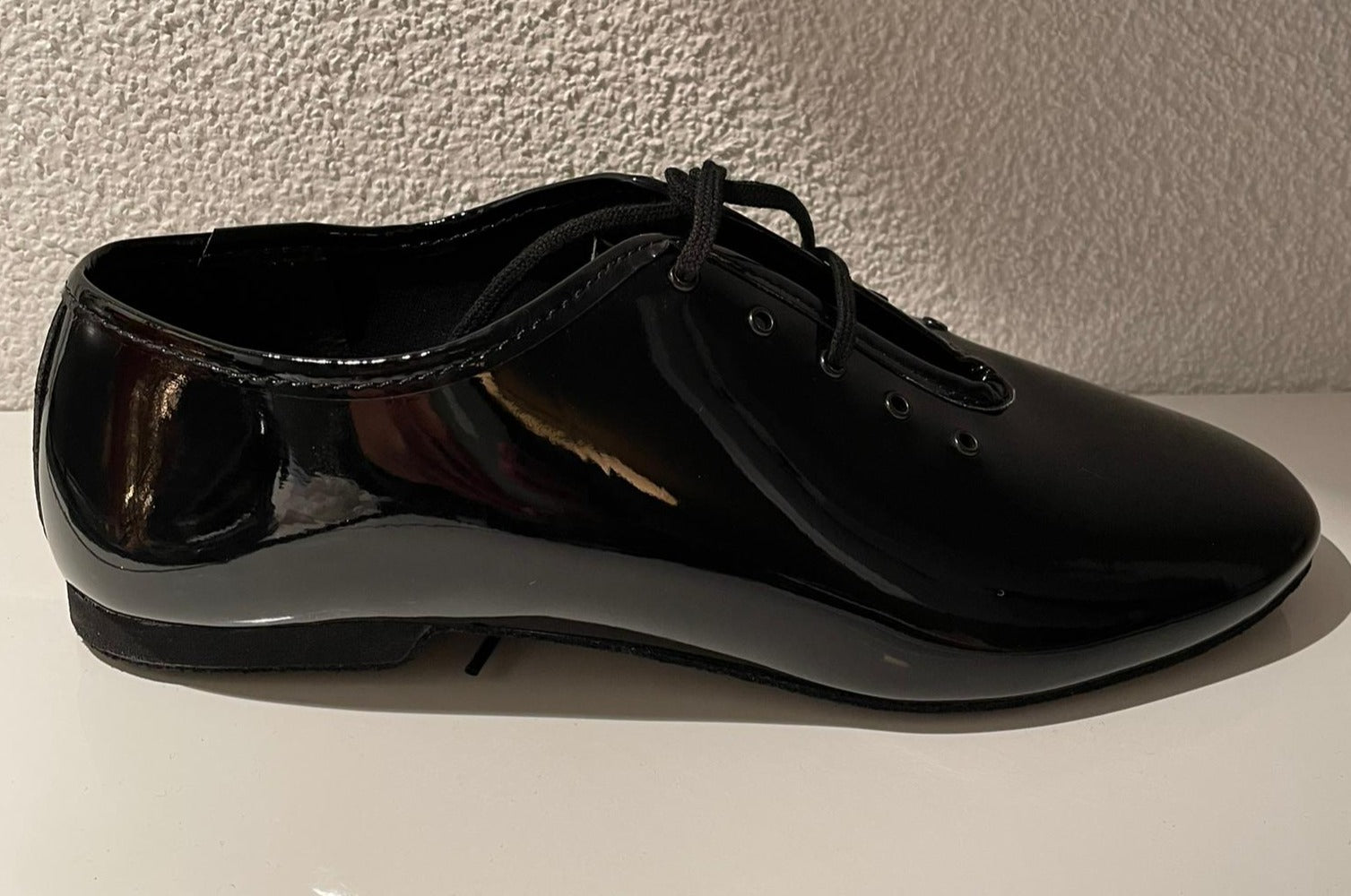 Lidmags 550/J03 Tanzschuhe aus schwarzem Lackleder mit Schnürsenkeln auf strukturierter weißer Oberfläche.