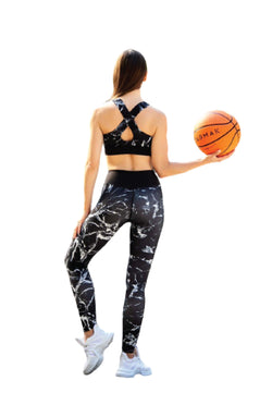 Eine Person im Sport-BH 176 Schwarz & Weiss von Lismina hält einen Basketball und blickt mit dem Gesicht nach hinten auf einen weißen Hintergrund.